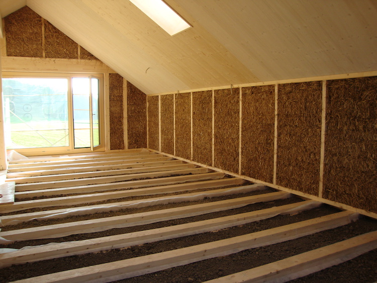 Bau eines Hauses aus Holz, isoliert mit Stroh und verputzt mit Lehm